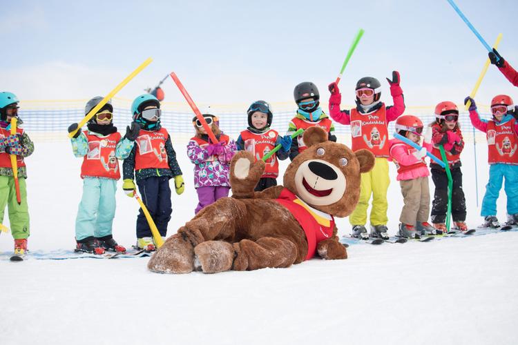 a group of children having fun with the ski school mascot