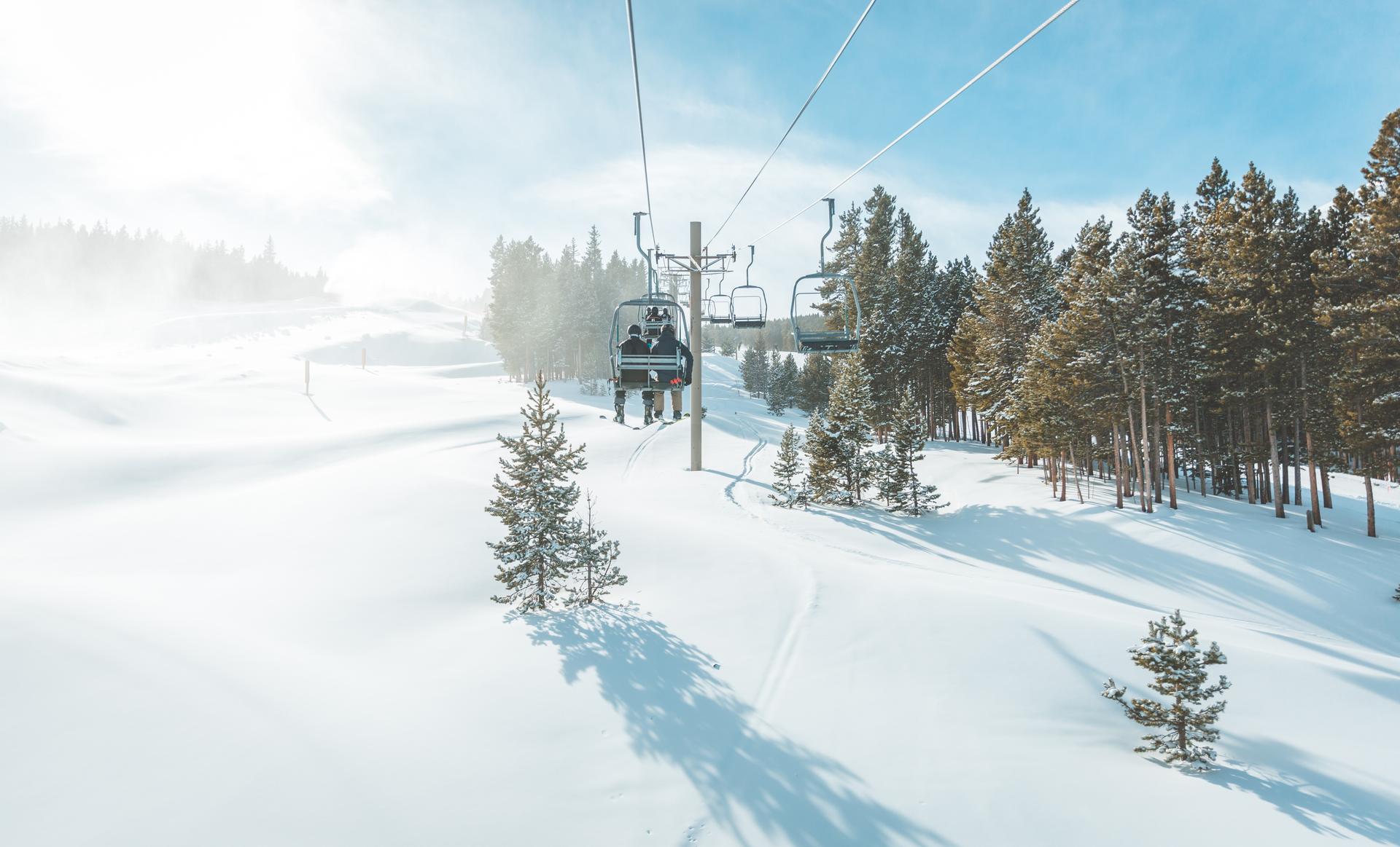 People on a two man ski lift over powder